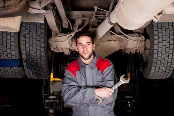 Certified mechanic inspecting under a truck with a wrench during truck repair in San Antonio TX