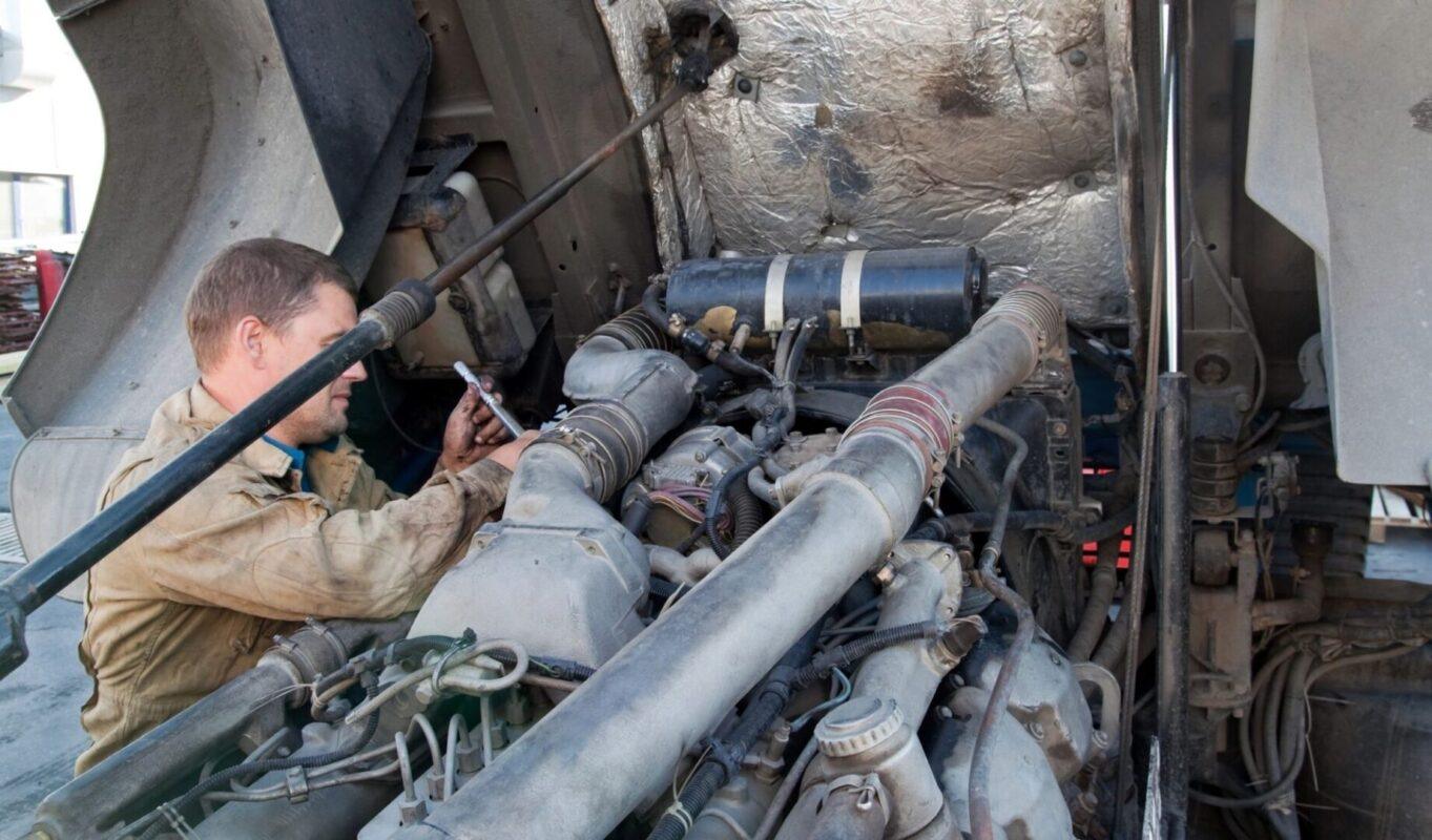 Mechanic performing heavy-duty diesel engine repair on truck with cab tilted up in San Antonio TX
